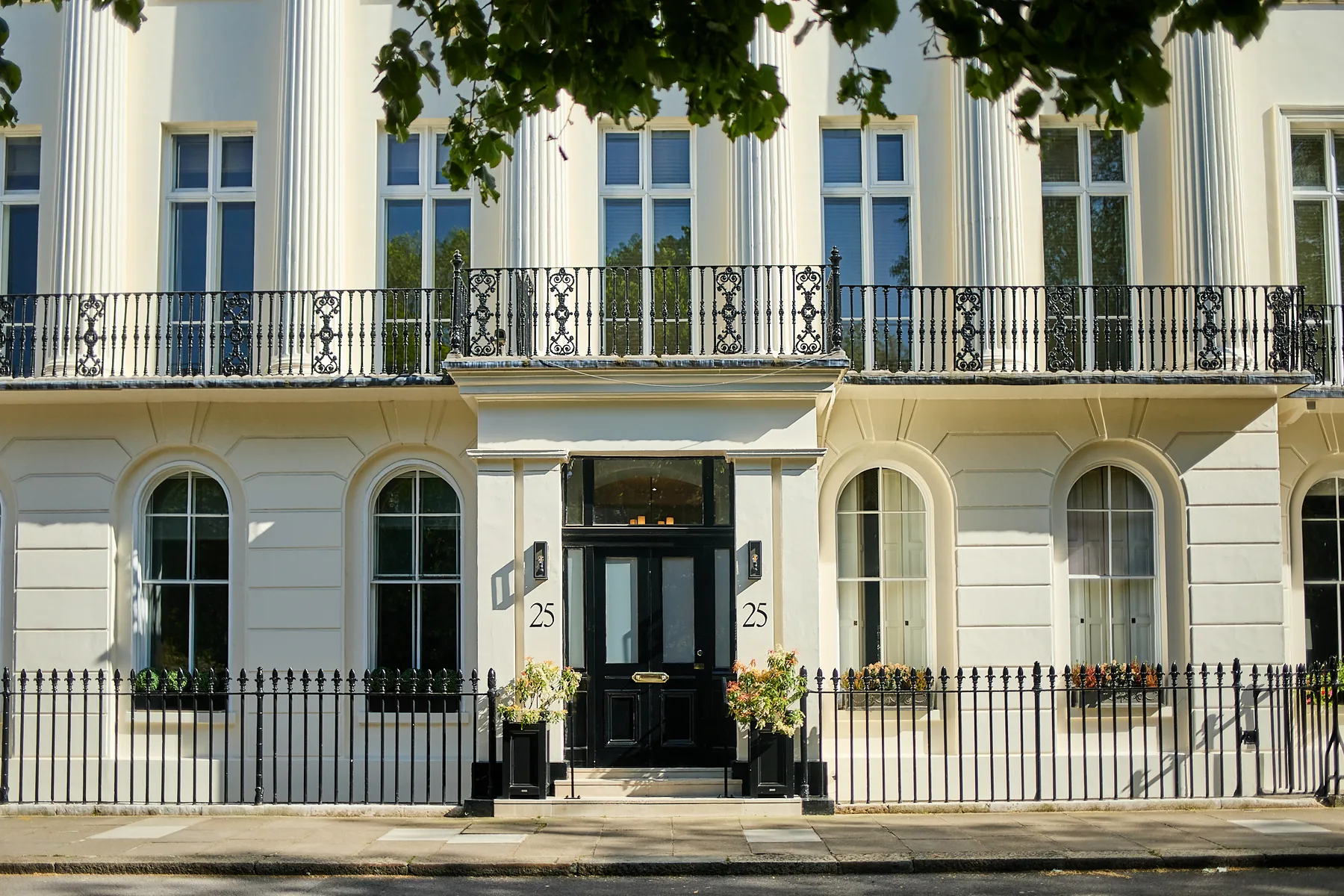 White stucco townhouse with a black front door and iron railings on a prime central London terrace