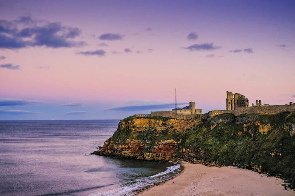 The ruins of Tynemouth Priory and Castle on the headland above King Edward's Bay at dusk, Tyne and Wear