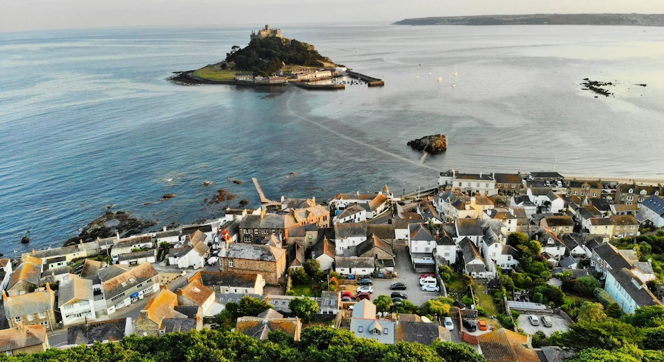 St Michael's Mount and its castle rising from the sea off Marazion, Cornwall, with the village rooftops in the foreground