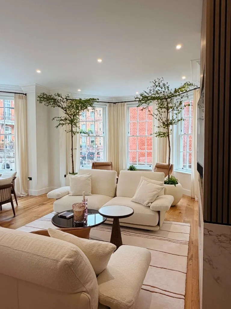 Reception room with cream seating and indoor trees on Mount Street, Mayfair