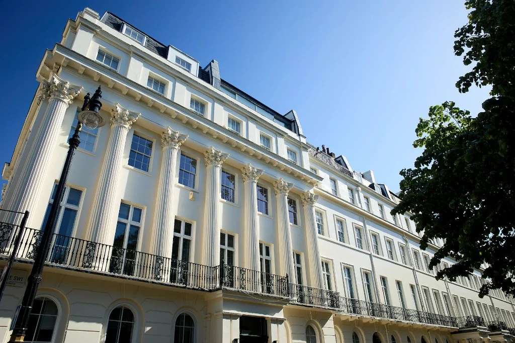 White neoclassical terrace in SW1 with Corinthian columns and a black iron balcony