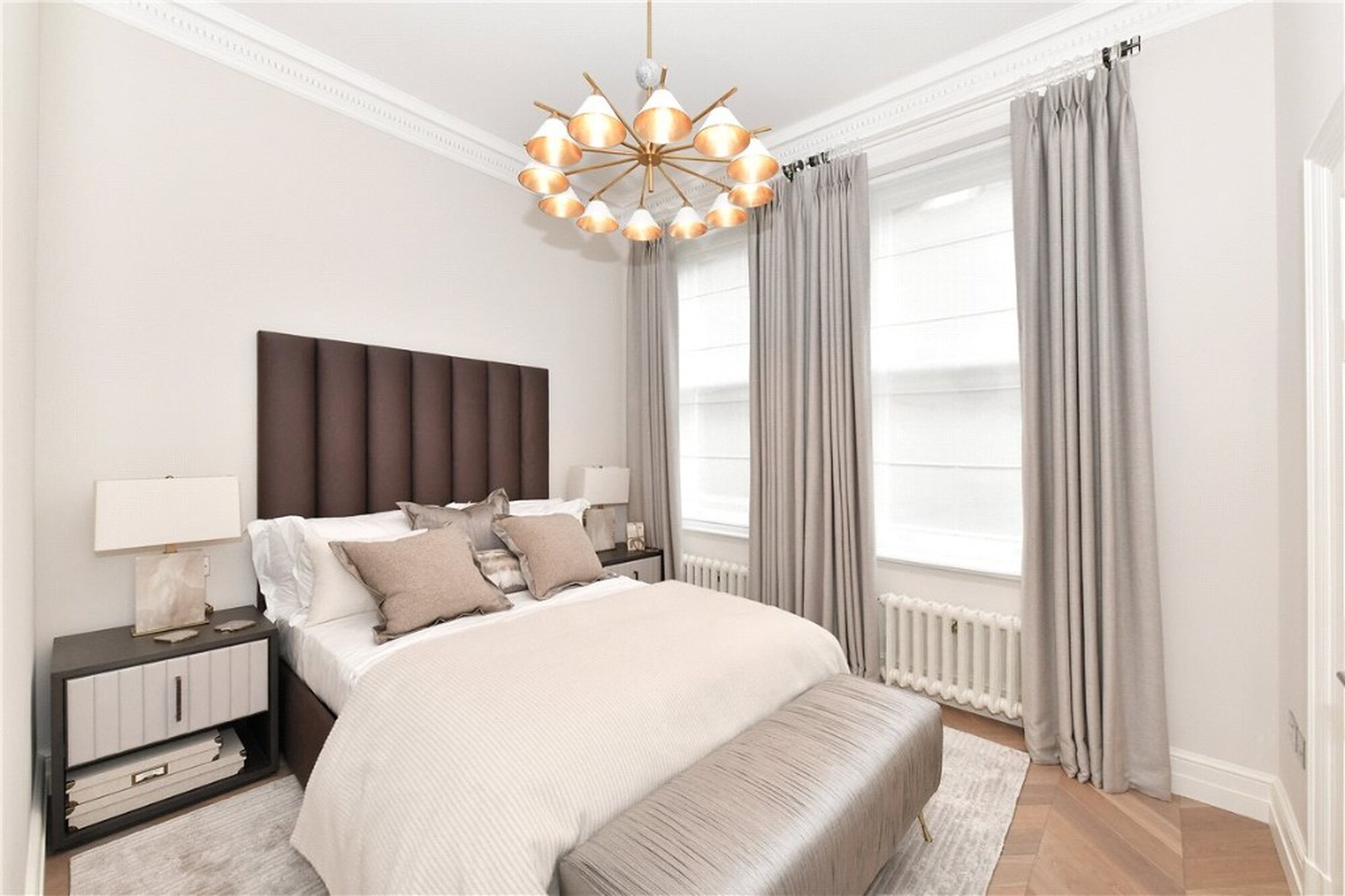 Mayfair bedroom with chocolate headboard, brass chandelier and herringbone flooring